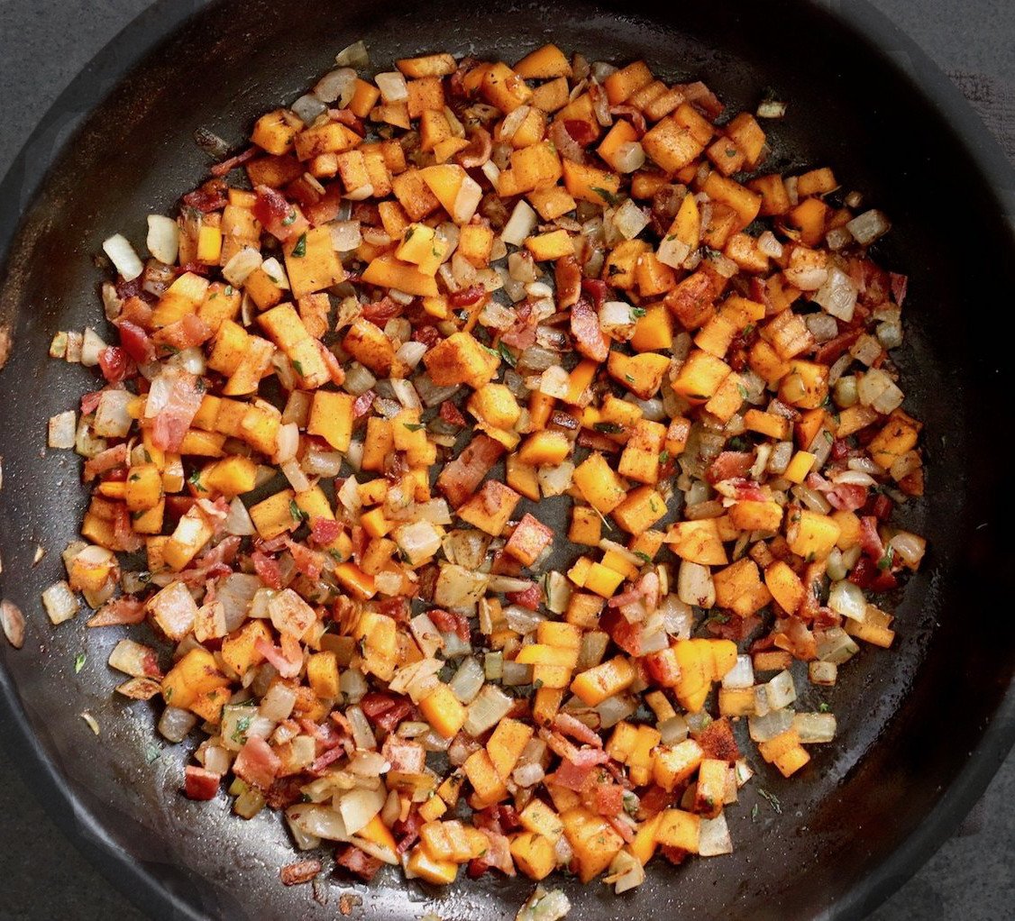 Mixture of chopped onion, persimmon and bacon in saute pan.