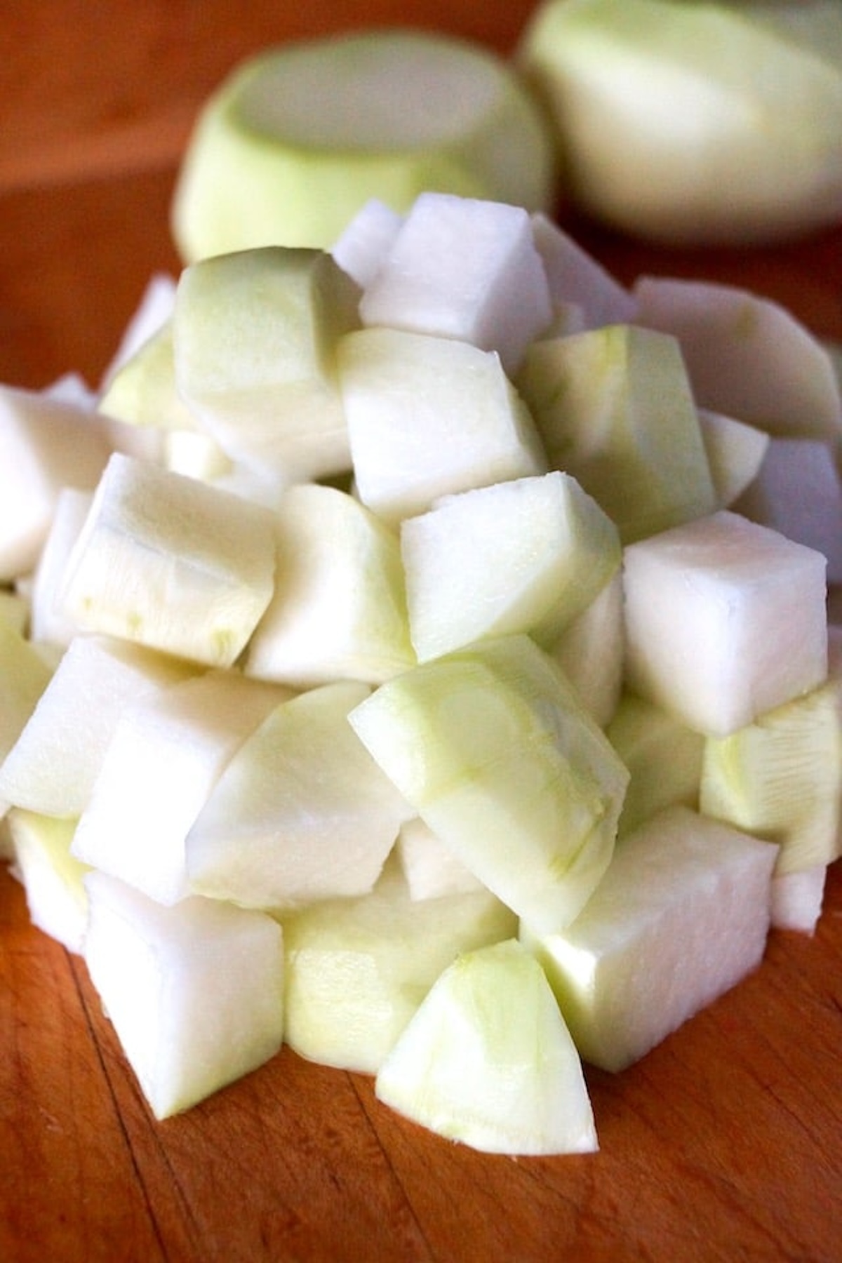 Roughly chopped, peeled kohlrabi on a cutting board.