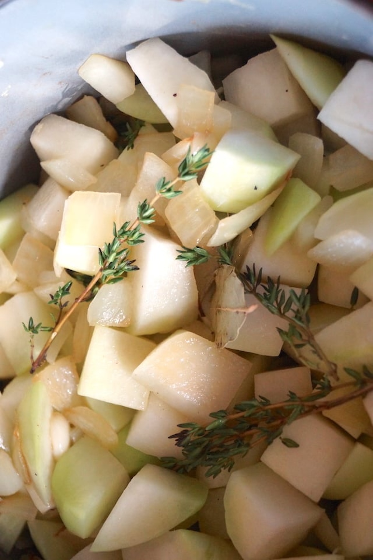 Roughly chopped raw kohlrabi with onion and thyme sprigs.
