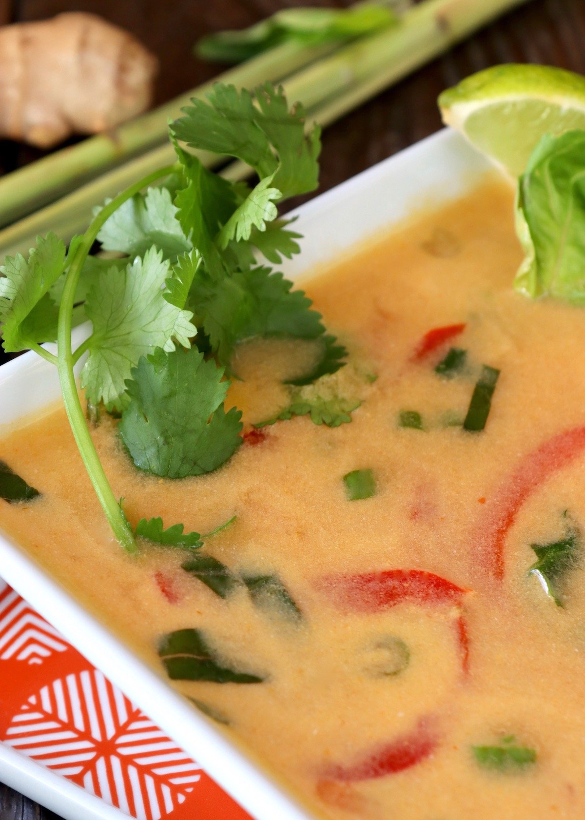 Square white bowl with ginger lemongrass soup and fresh cilantro