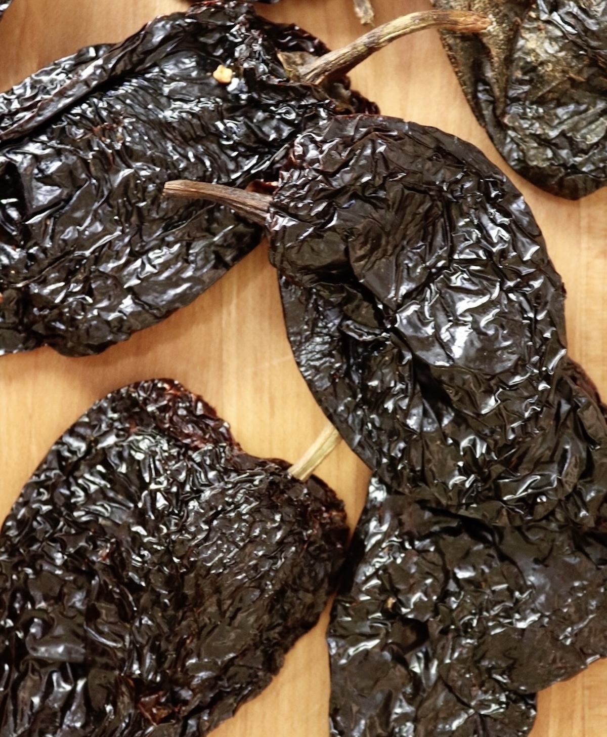 A few Ancho chiles on a cutting board.