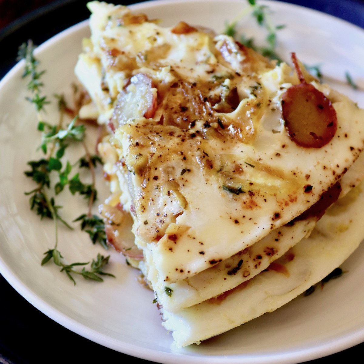 Three stacked slices of an egg white frittata on a white plate.
