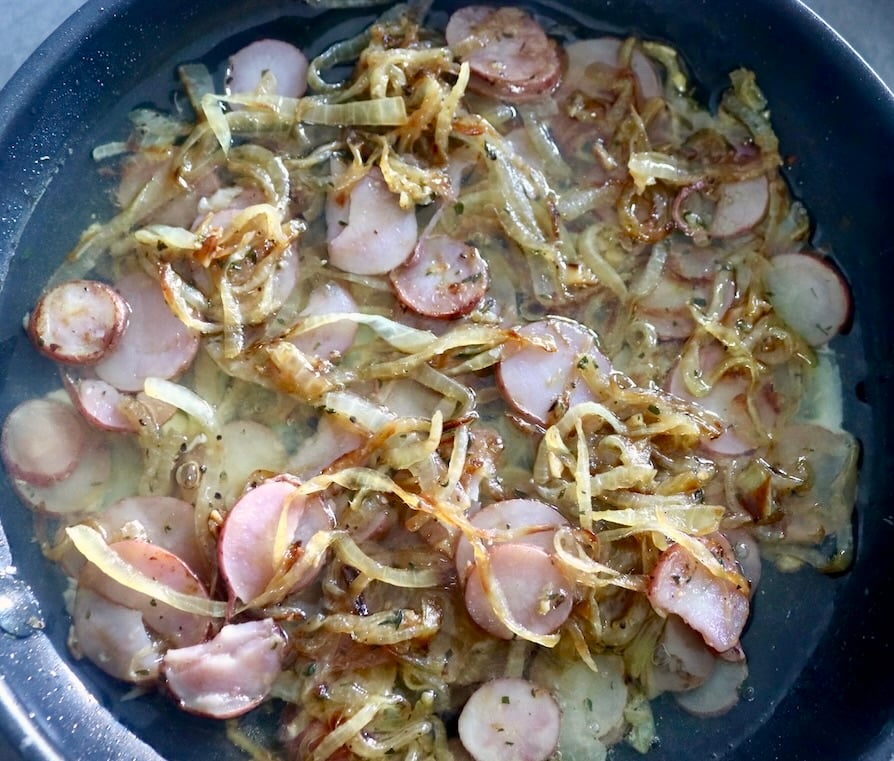 Egg whites in a skillet with lots of sliced pink potatoes and caramelized onion.