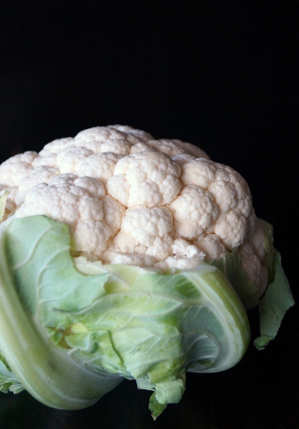 One head of cauliflower on black background.