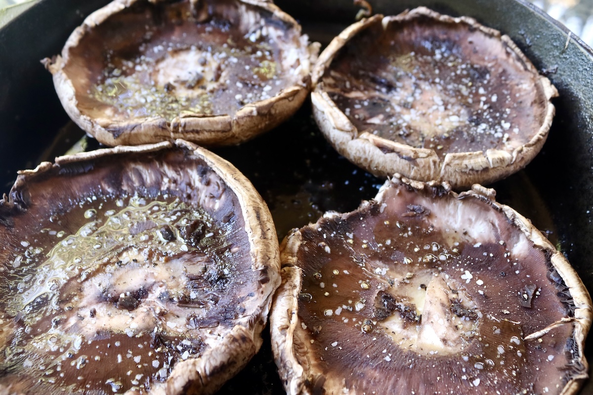 4 portobello mushrooms in a cast iron skillet, round side down.