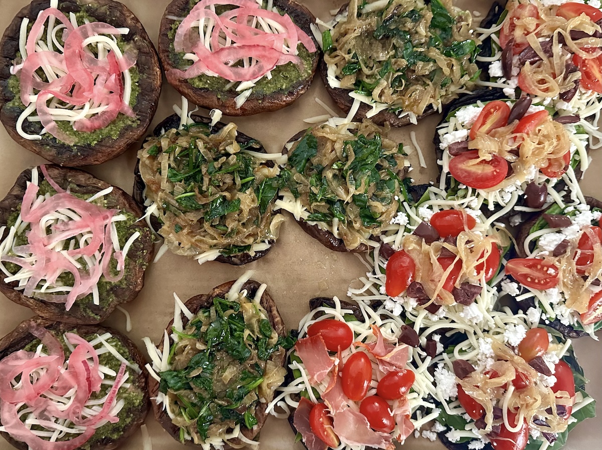 14 Portobello mushroom caps filled with different pizza toppings, from spinach and caramelized onion, to mozzarella and tomatoes to pesto and pickled red onion.