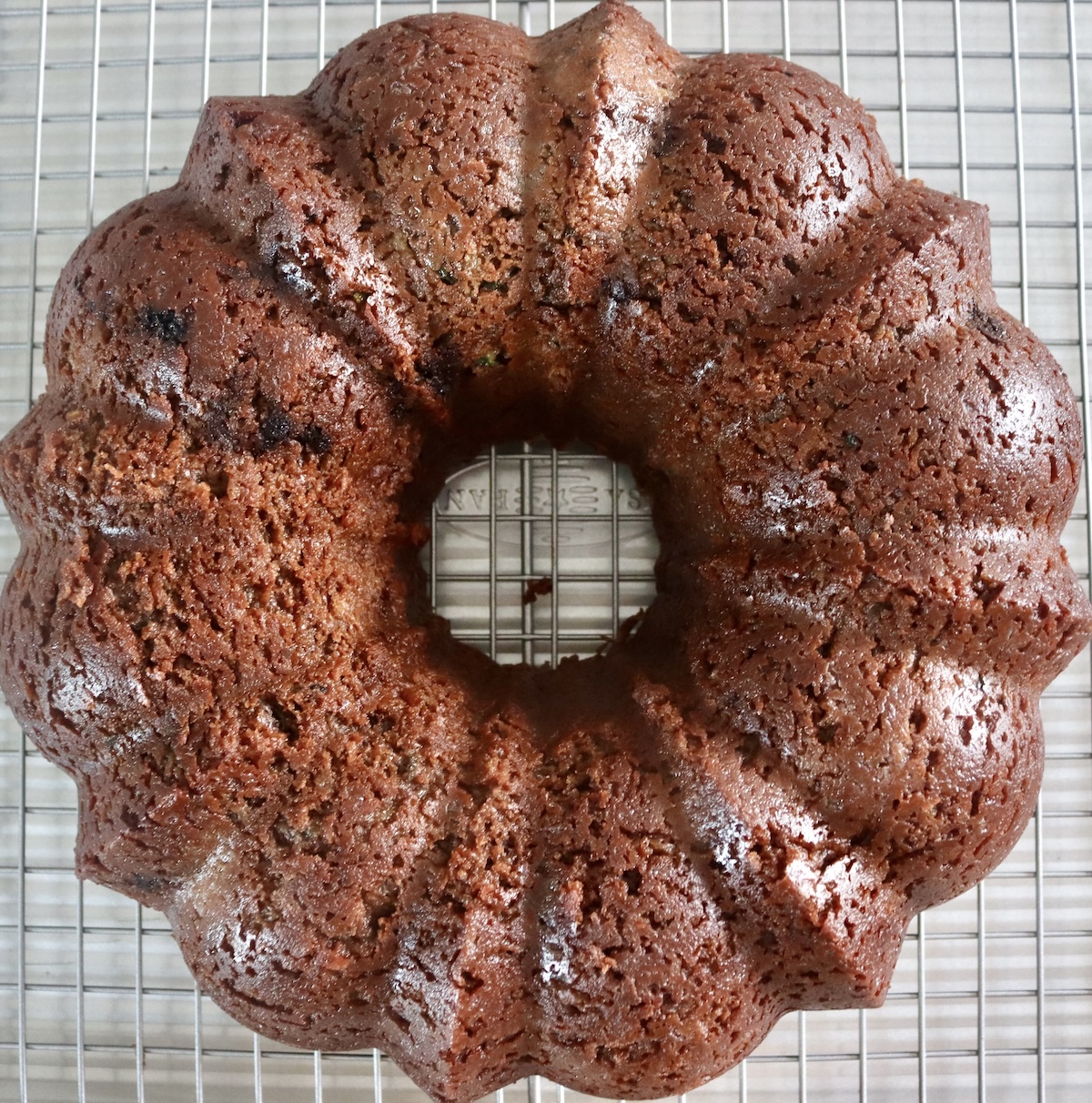 Finished chocolate bundt cake with zucchini on a baking rack.