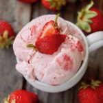 Top view of Strawberry Swirl No-Churn Ice Cream in a small white mug with strawberry on top.