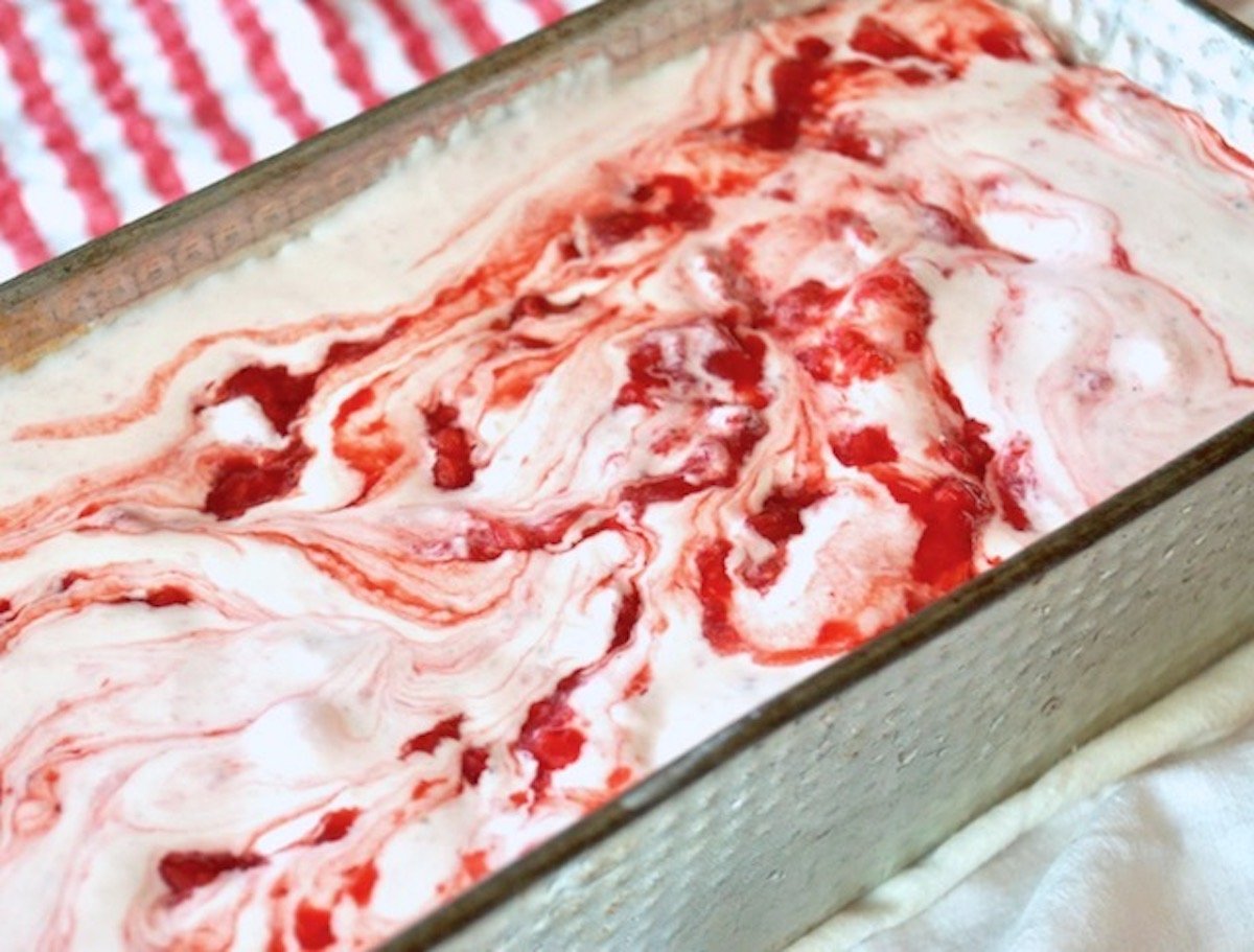 Swirled Strawberry Ice Cream in a bread pan on red and white striped cloth.