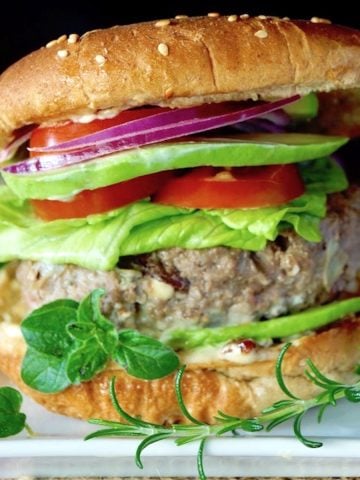 Close up of a Grilled Mediterranean Burger in a bun with all the fixins.
