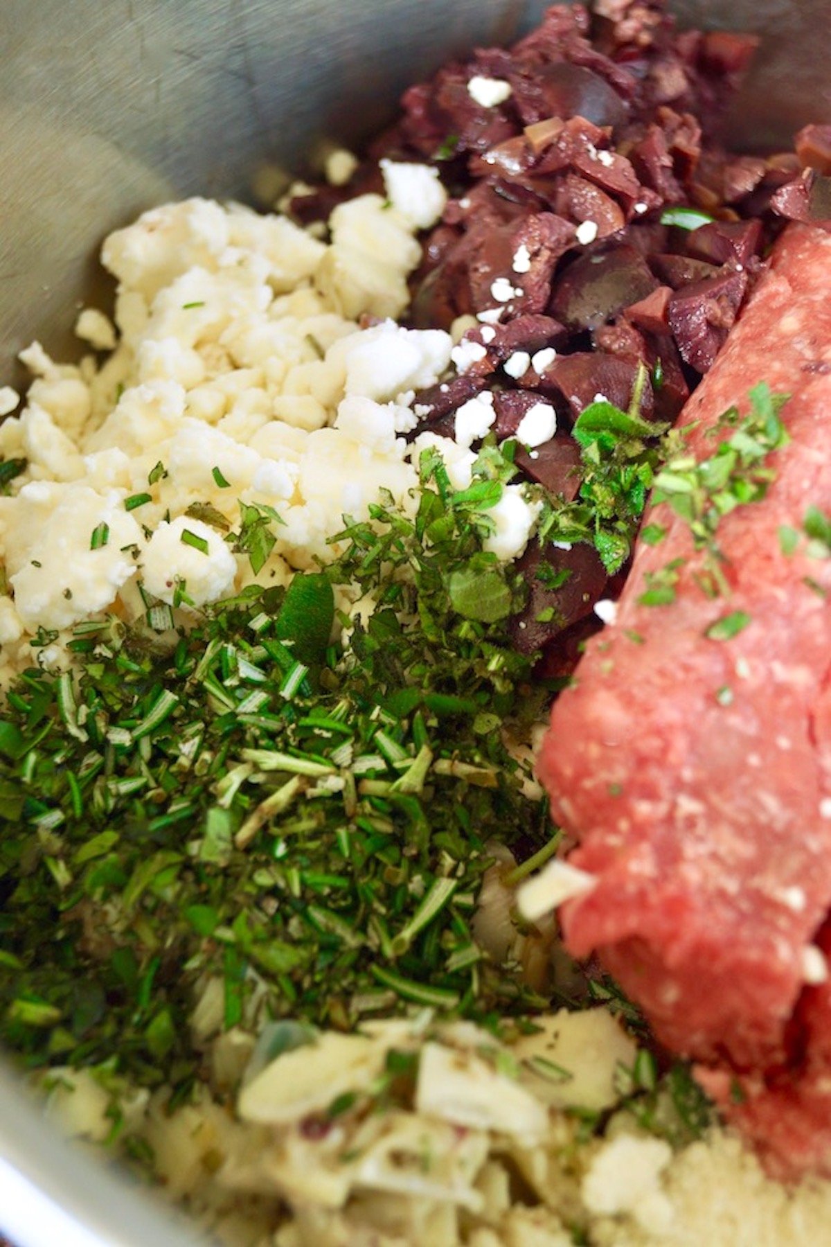 Bowl of ingredients for Grilled Mediterranean Burgers with chopped herbs on top.