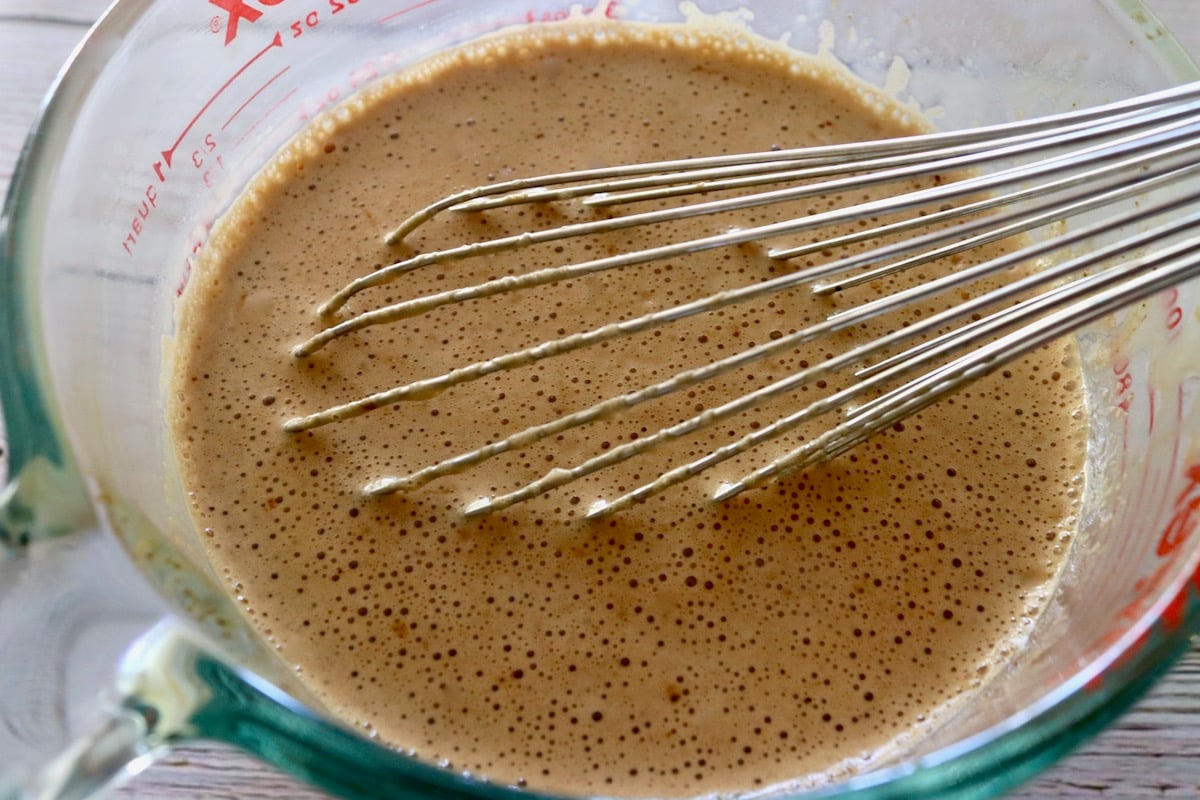 Milk whisked with espresso powder in a glass measuring  cup.