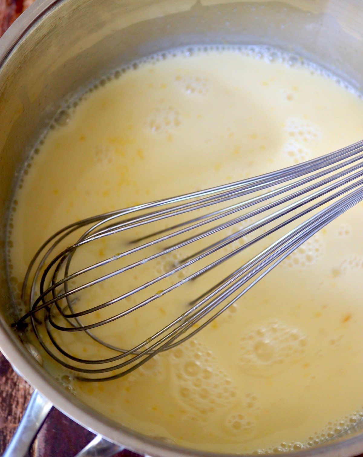 Milk-egg mixture in a stainless steel sauce pot with a whisk.