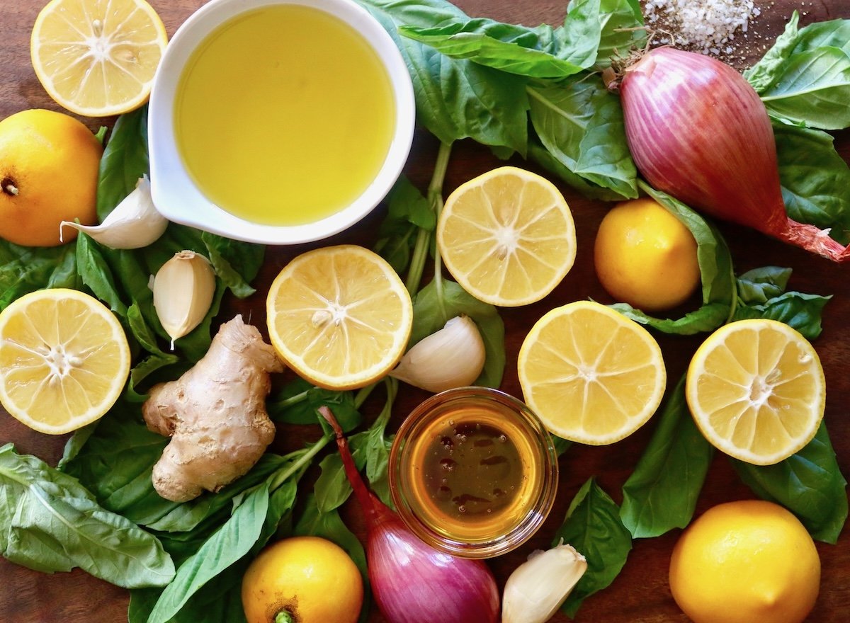 Cutting board full of lemon halves, shallots, basil and ginger.