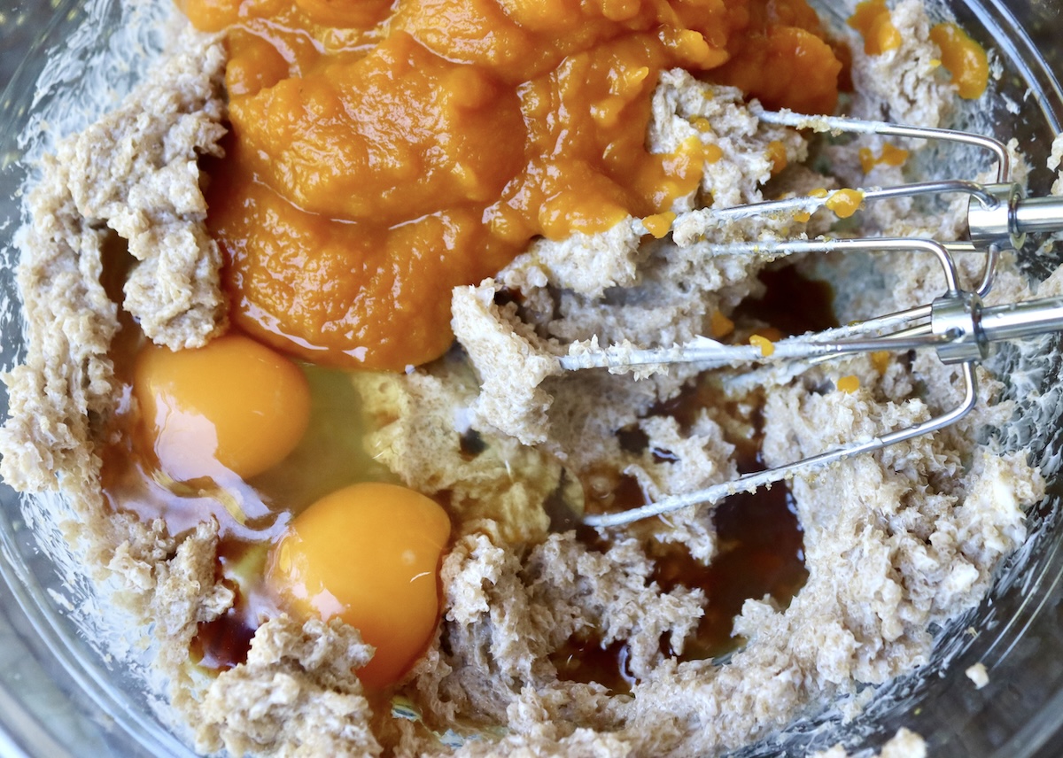 Pumpkin-Coffee-Cake-with-Streusel-and-Caramel Butter and brown sugar mixed with electric beaters in a glass bowl, with pumpkin puree, eggs and vanilla on top.