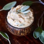 Small wooden bowl with brown butter and sage leaves inside.