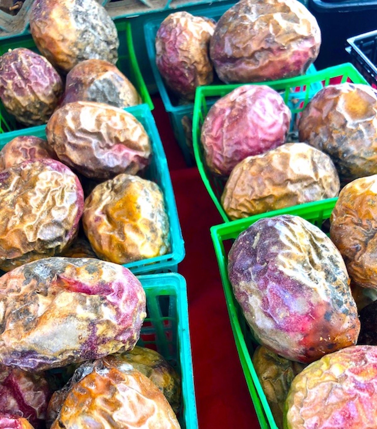 Ripe and wrinkled passion fruits in small green plastic boxes. 