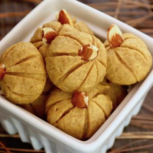 Several Pumpkin Almond Flour cookies in a white ceramic box on wood surface.