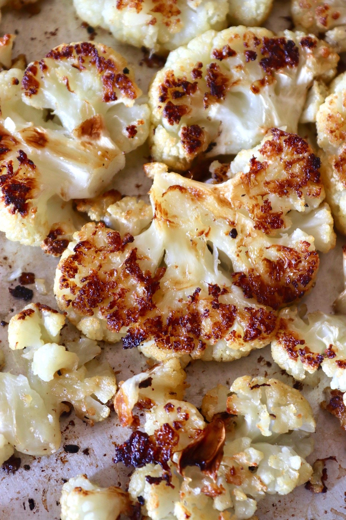 Sheet pan full of smashed cauliflower florets that are golden brown.
