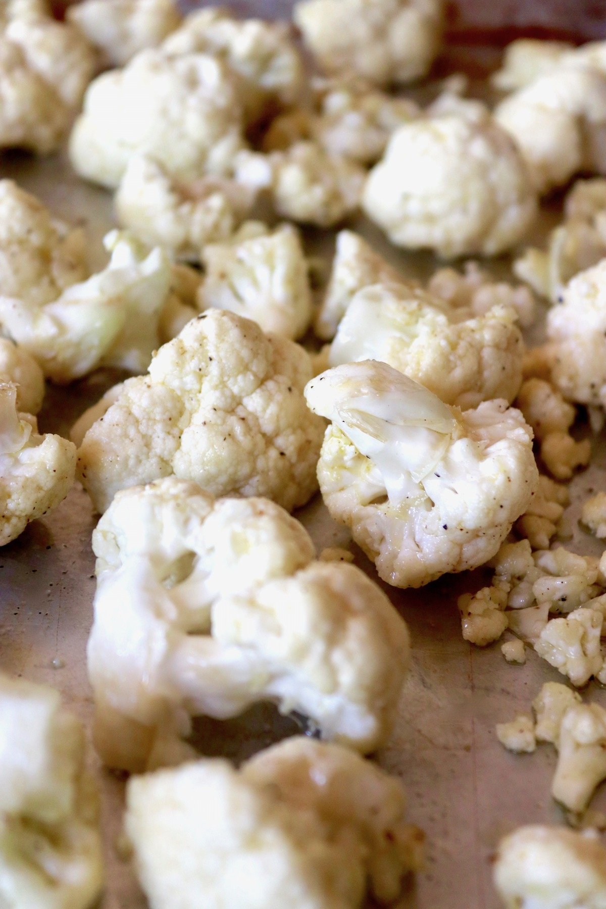 Raw pieces of cauliflower on a sheet pan.