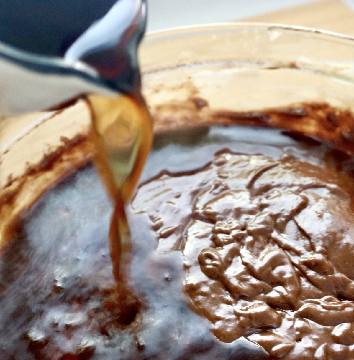 Coffee being poured into gluten-free chocolate cake batter in a mixing bowl.