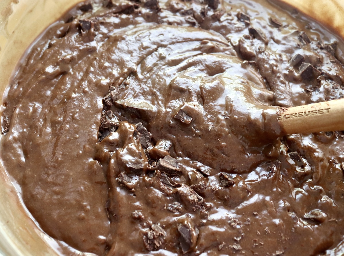 Batter for gluten-free dark chocolate cake in a bowl with a wooden spoon handle.