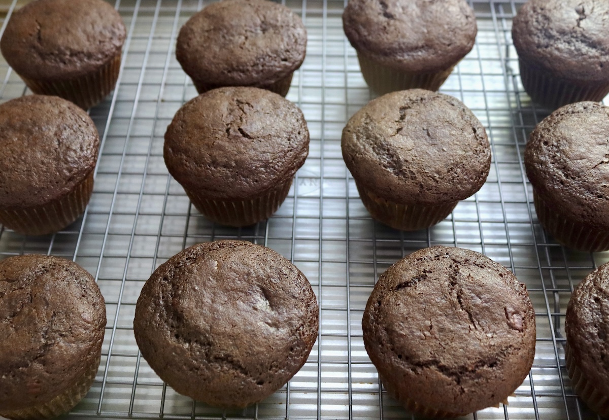 Several gluten-free chocolate cupcakes on a cooling rack.