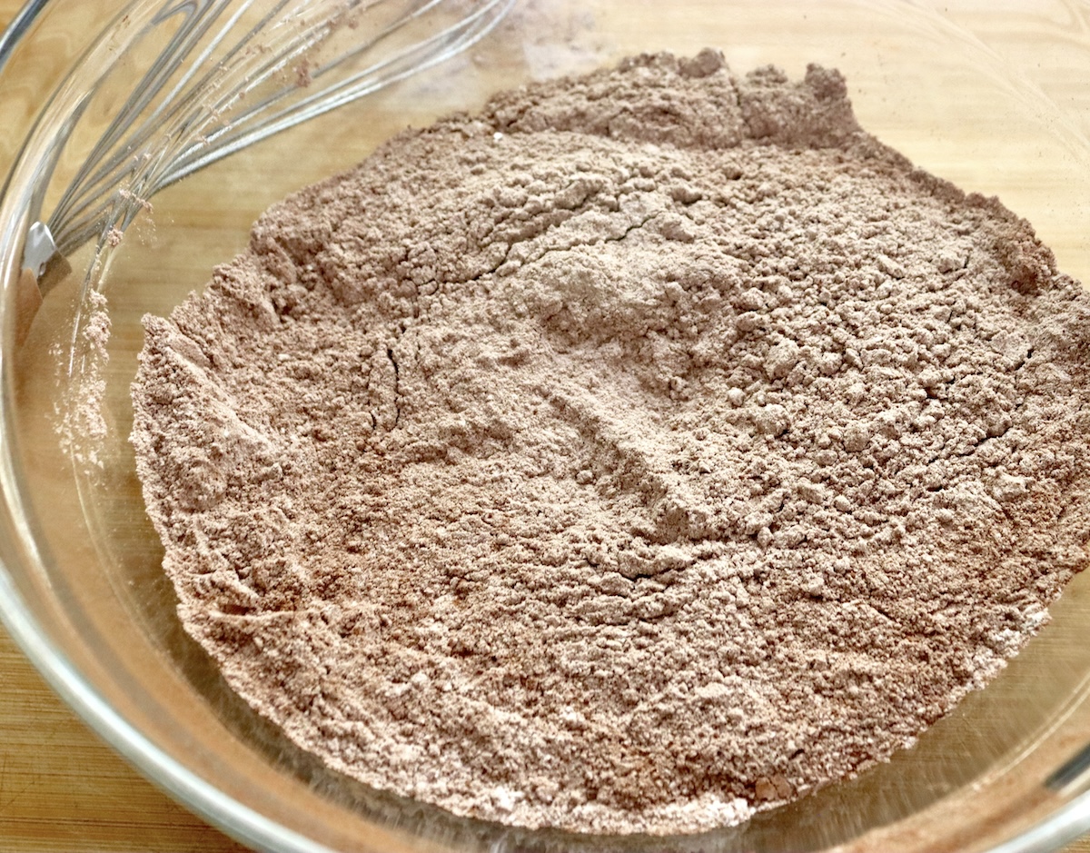 Dry ingredient mixture for gluten-free dark chocolate cake, including cocoa powder, salt, baking soda and powder and gluten-free all purpose flour.