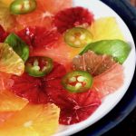 Close up of Citrus carpaccio on a white plate, orange, blood orange and grapefruit, with jalapeno rings.