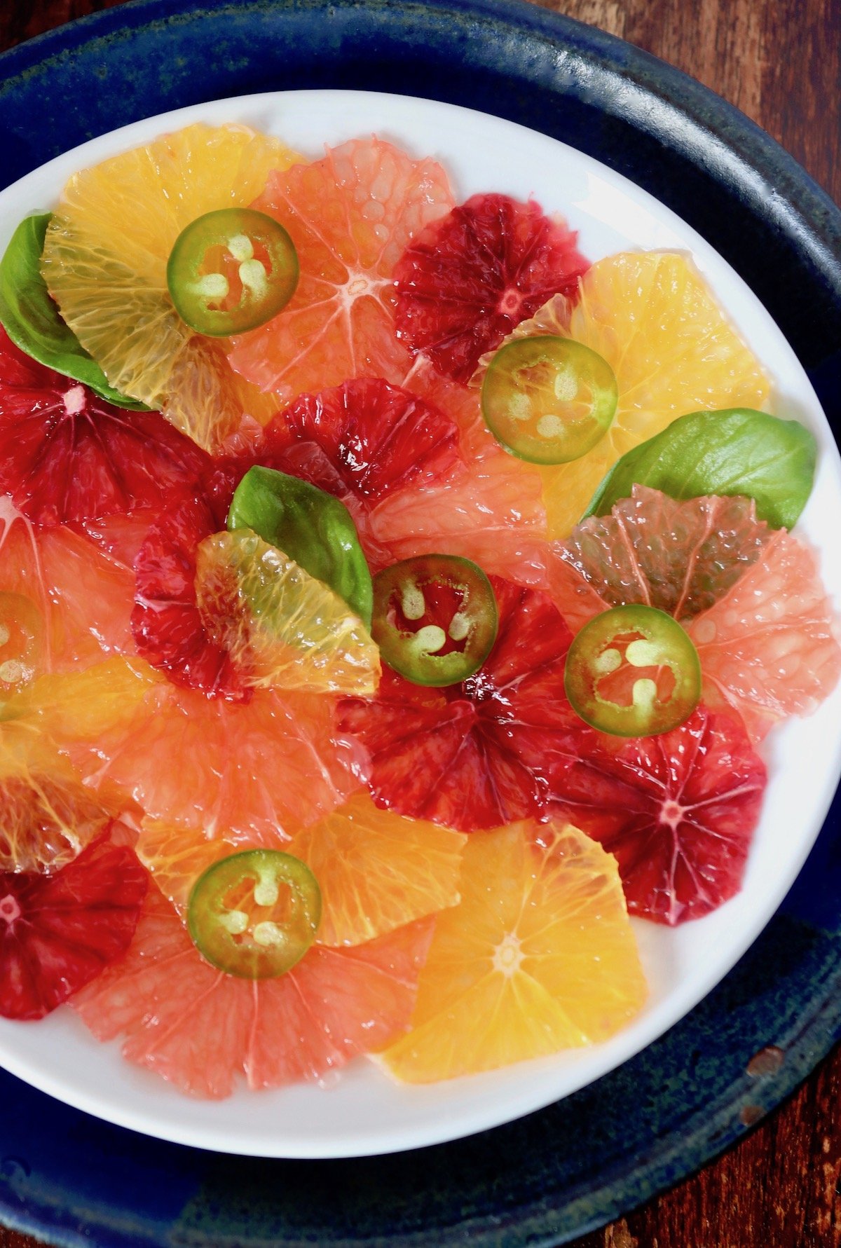 White plate lined with super thin slices of citrus (orange, grapefruit and blood orange), topped with jalapeno rings.