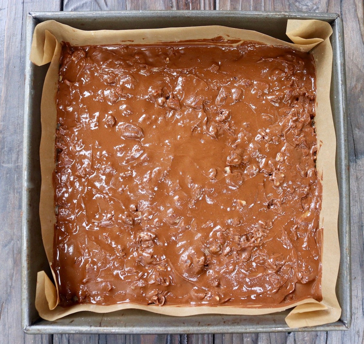Chocolate filling a parchment paper-lined square baking pan.