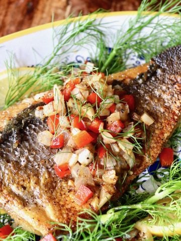 Seared sea bass, skin side up, on a bed of fennel sprigs with salsa on top.