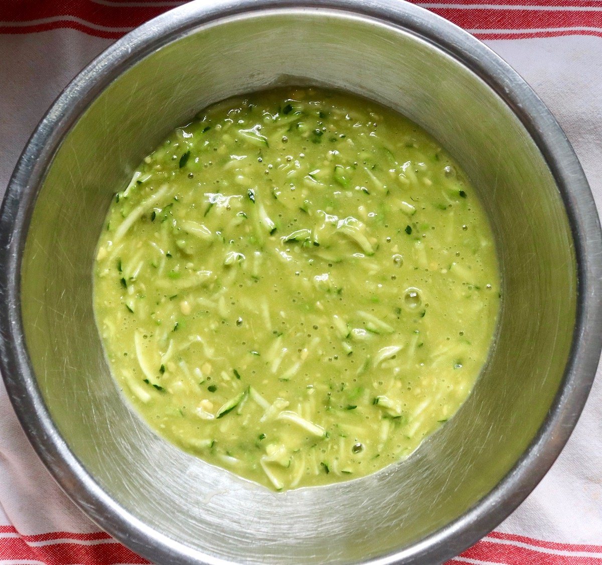 Green-ish mixture of avocado, zucchini and eggs with sugar for avocado zucchini bread batter.