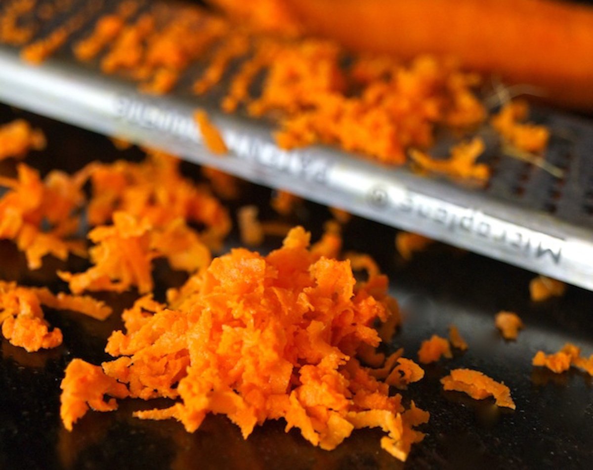 Grated fresh turmeric on a dark surface with micro plane zester.