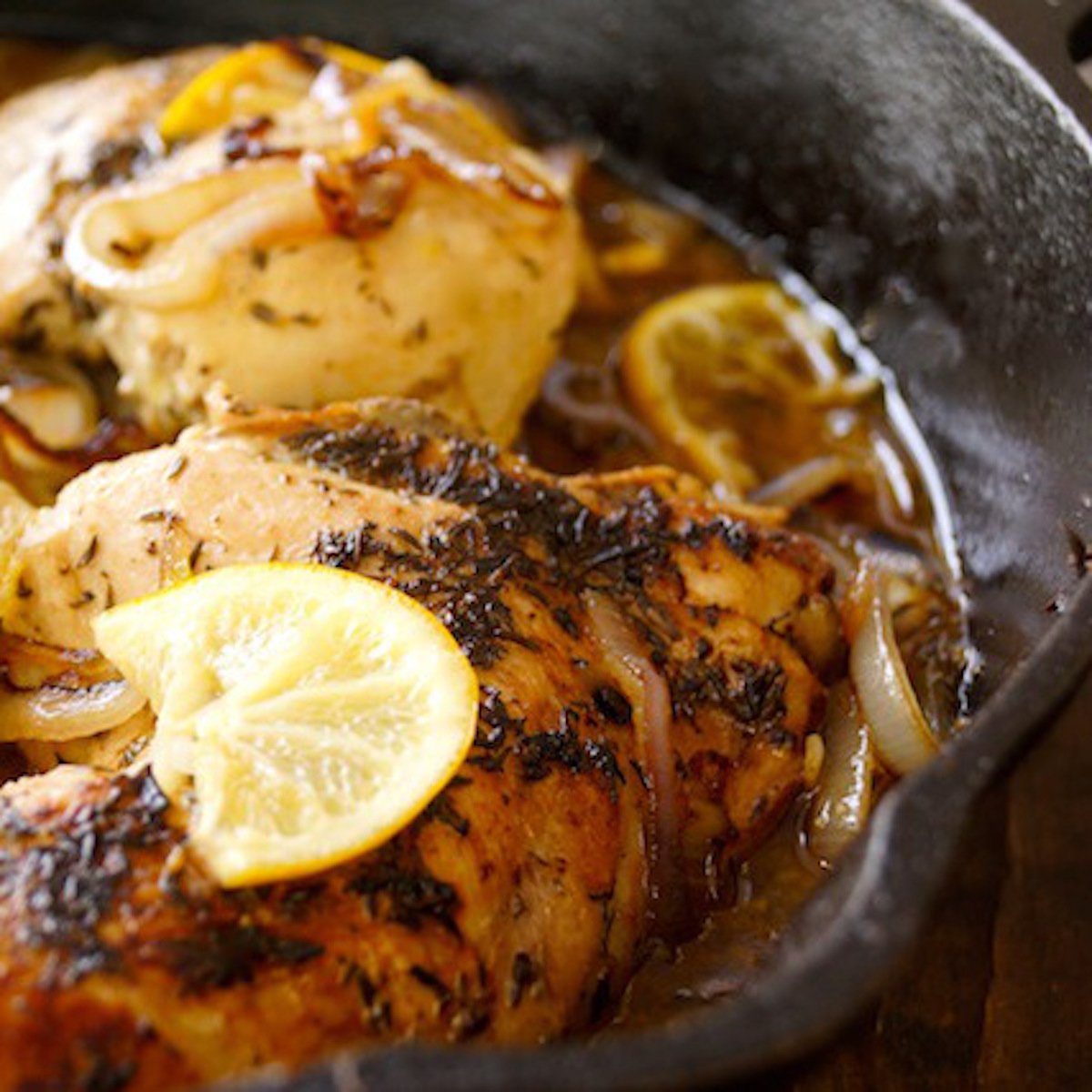Skillet Braised Chicken in cast iron pan with slices of lemon.