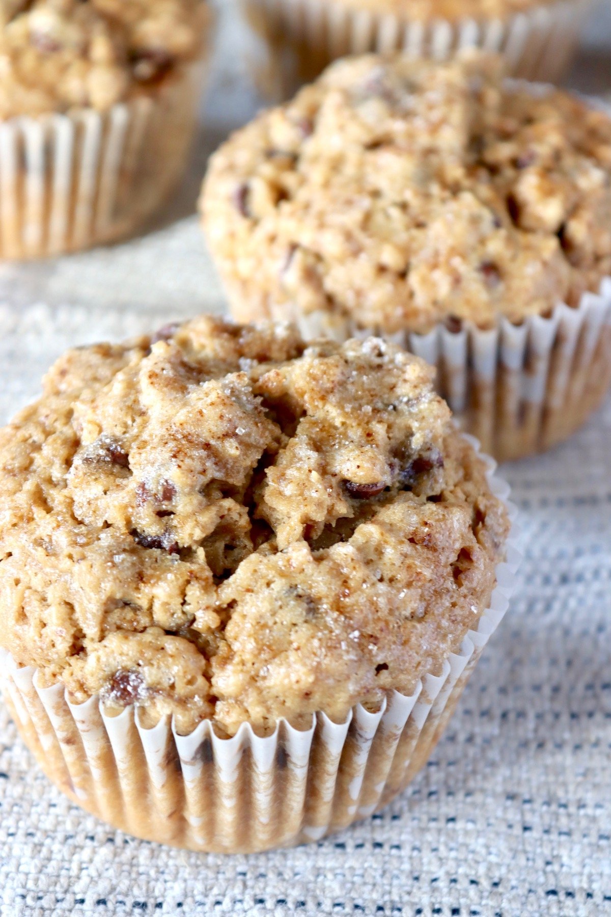 A few cappuccino muffins in paper liners, on textured beige cloth.