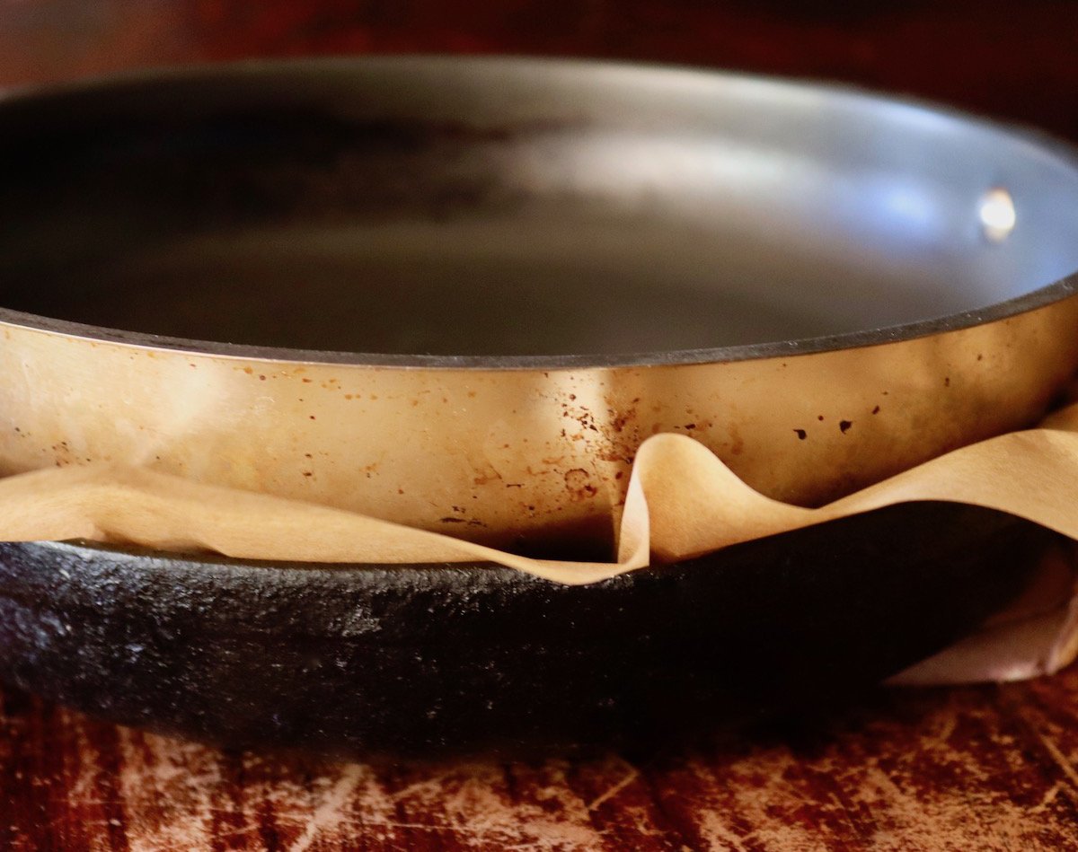Two skillets, one on top of the other, with parchment paper between them.