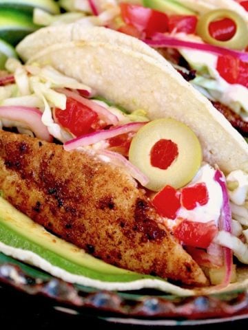 Close up of a blackened fish taco with sliced Spanish olives on top.