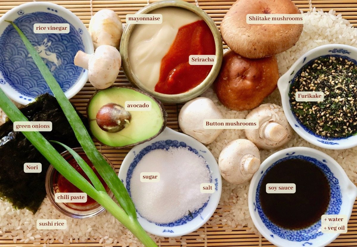 Ingredients for Sushi Bake on sushi mats, including rice, salt, sugar, avocado, mushrooms, scallions and soy sauce.