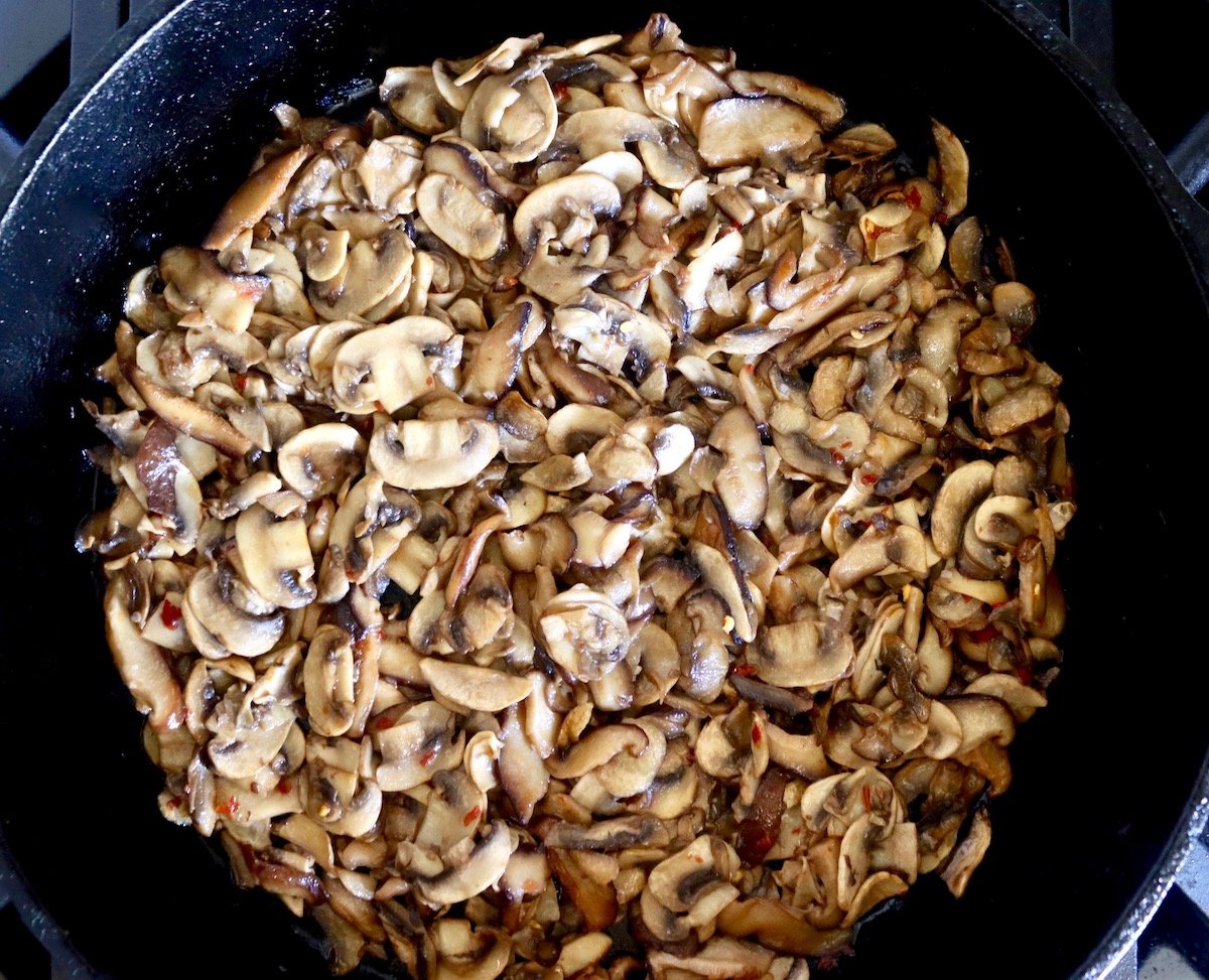 Cast iron skillet with sauteed mushroom slices.