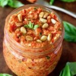 Top view of a small jar filled with red pepper pesto.