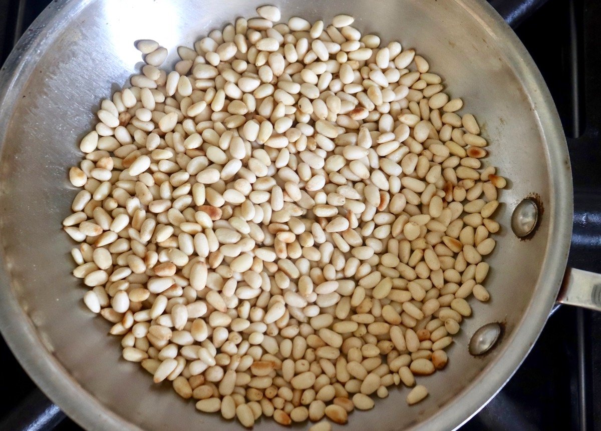 raw pine nuts in saute pan.