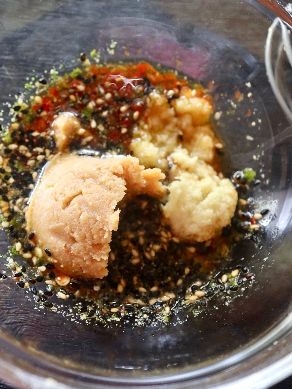 Glass bowl with Furikake, chili paste, miso paste, mirin and soy sauce.