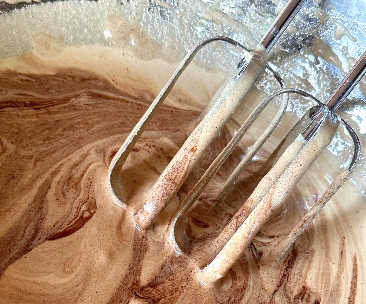 Brownie batter in a mixing bowl with beaters.