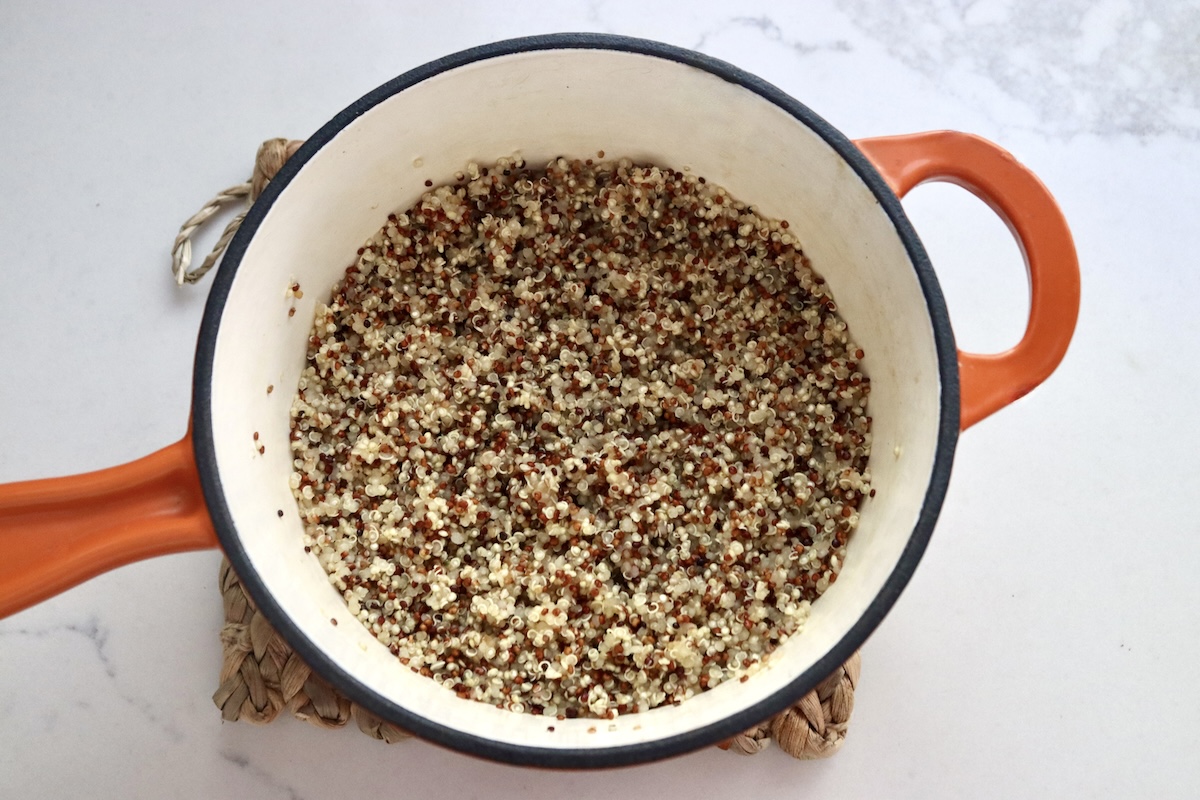 Cooked quinoa in a small orange-handled pot.
