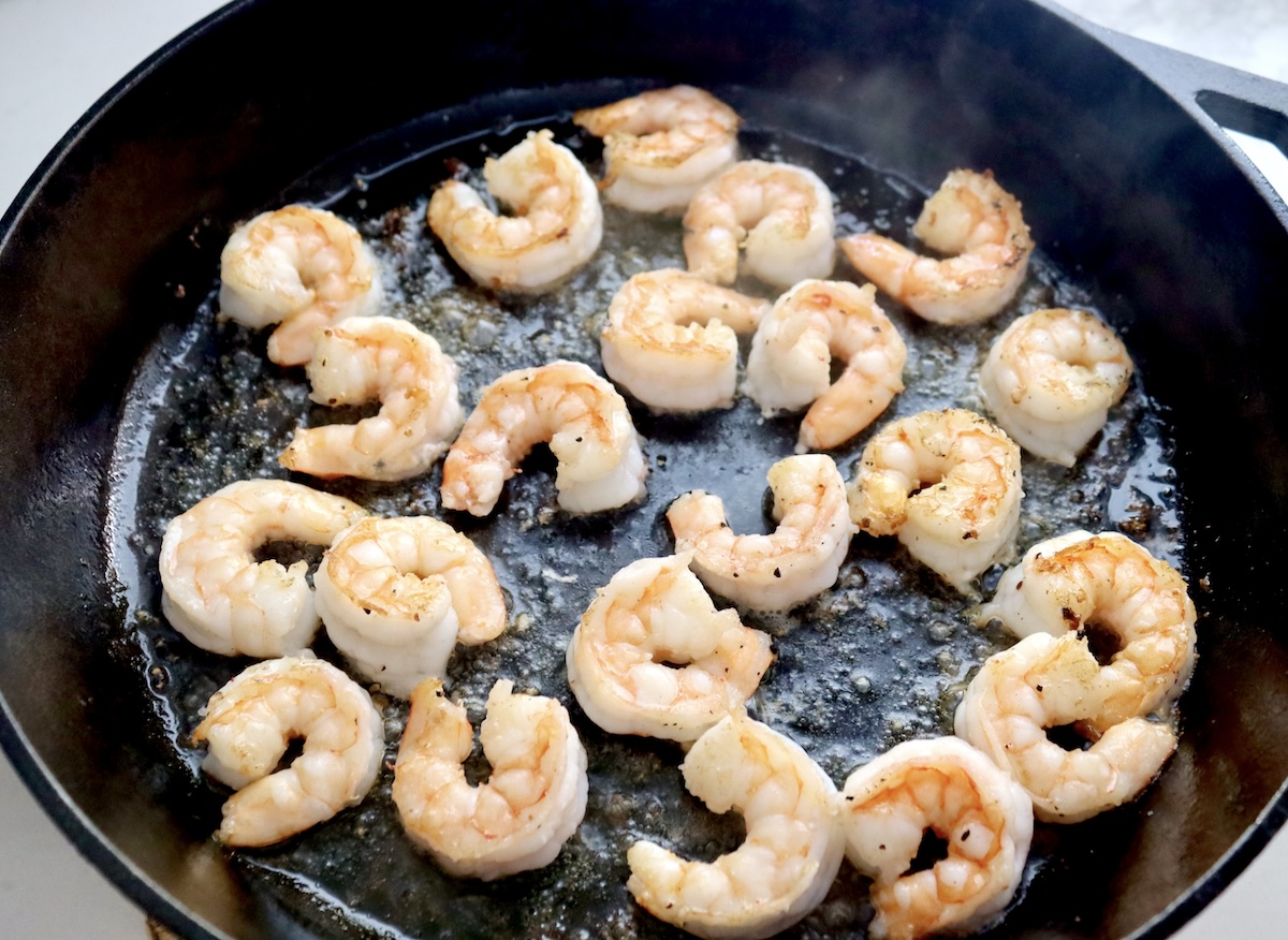 Pink, cooked shrimp in a cast iron skillet.