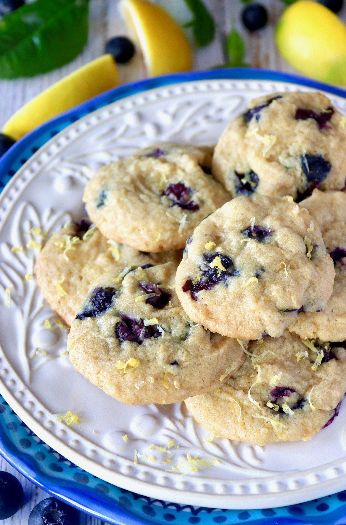 Cream-colored plate on top of a blue-rimmed plate with layered lemon blueberry cookies.