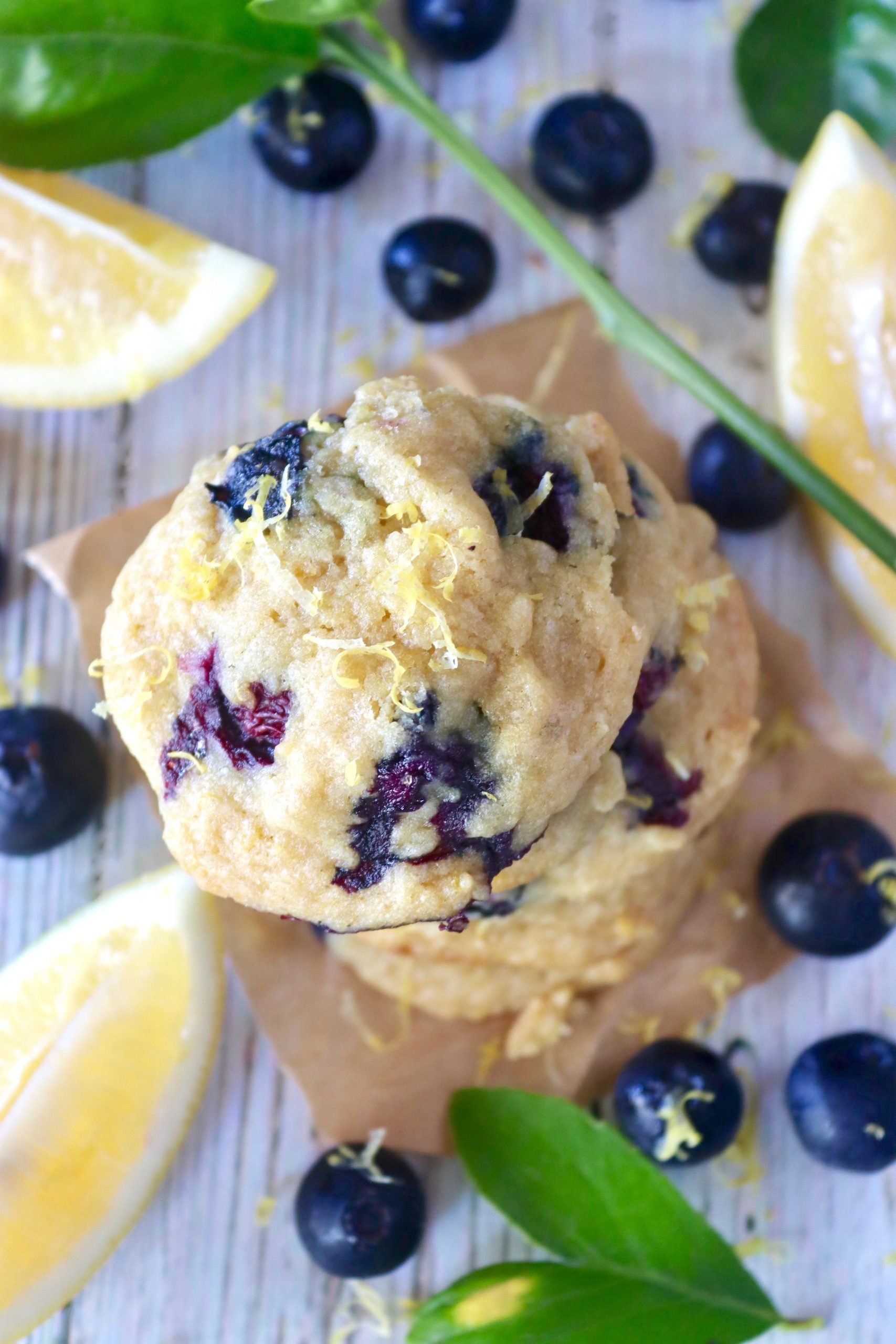 Top view of a stack of lemon cookies with blueberries with blueberries and lemon slices around them.