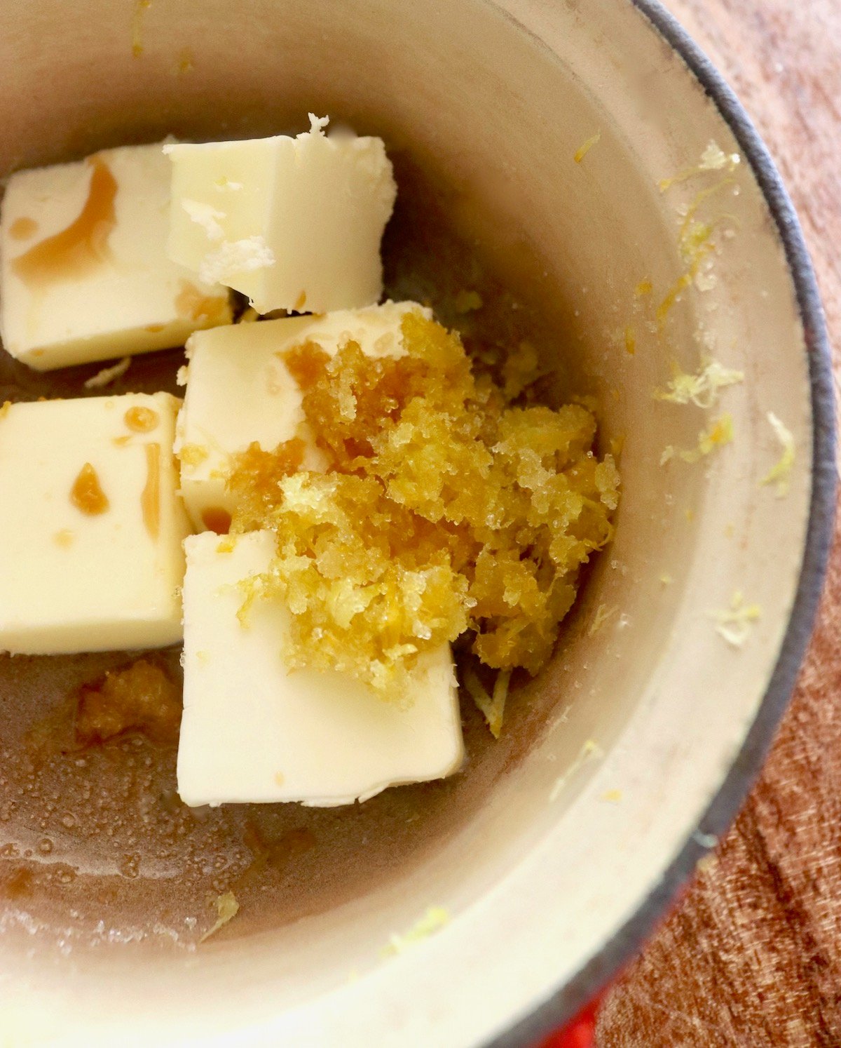 Chunks of butter, lemon sugar and vanilla in a cream-colored pot.
