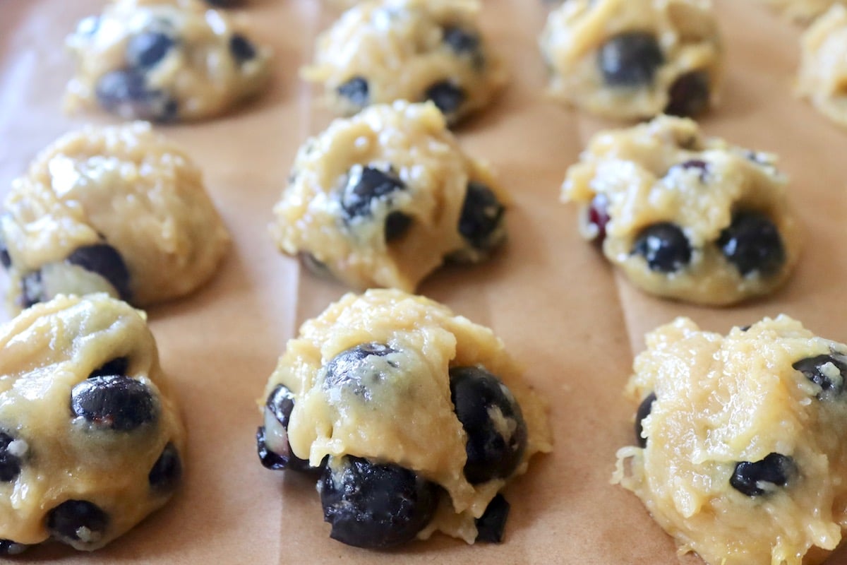 Several balls of blueberry cookie dough on a parchment lined baking sheet.